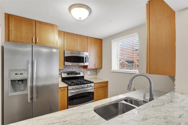 kitchen with stainless steel appliances, backsplash, light stone counters, and sink