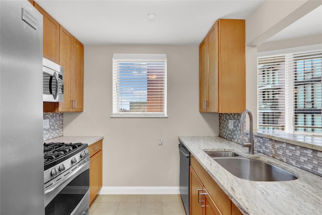 kitchen featuring decorative backsplash, sink, stainless steel appliances, light tile patterned floors, and light stone counters