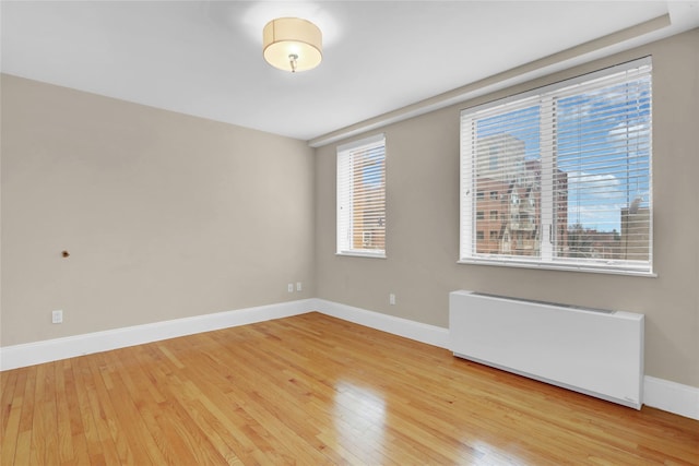 unfurnished room with radiator and light hardwood / wood-style flooring