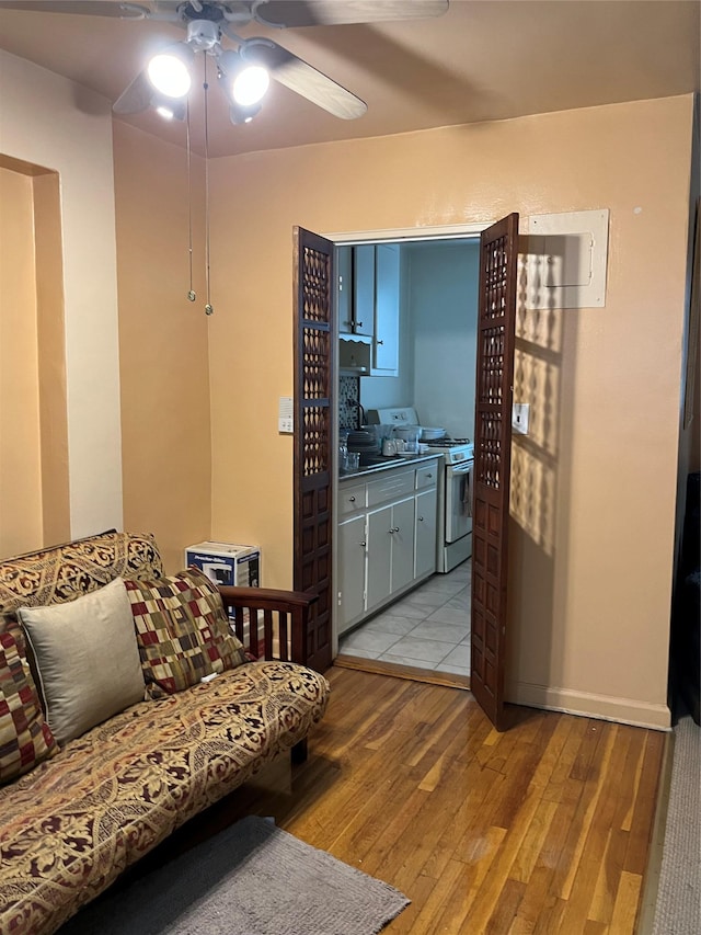 living room with ceiling fan, sink, and light wood-type flooring