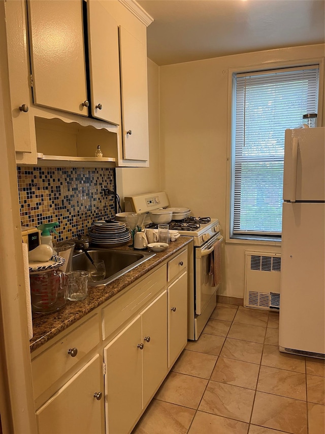 kitchen featuring decorative backsplash, white appliances, light tile patterned flooring, radiator, and white cabinets