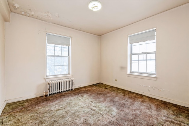 unfurnished room featuring radiator, a wealth of natural light, carpet flooring, and ornamental molding