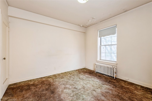 spare room with dark colored carpet, crown molding, and radiator heating unit