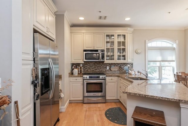 319 Trotting Ln Unit 23, Westbury, NY 11590 - kitchen with stainless steel appliances, a peninsula, crown molding, light wood-style floors, and decorative backsplash