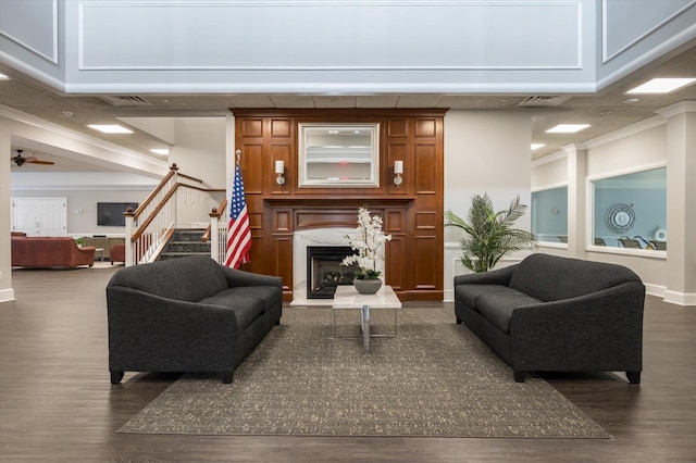 living room with ceiling fan, dark wood-type flooring, a high end fireplace, and crown molding