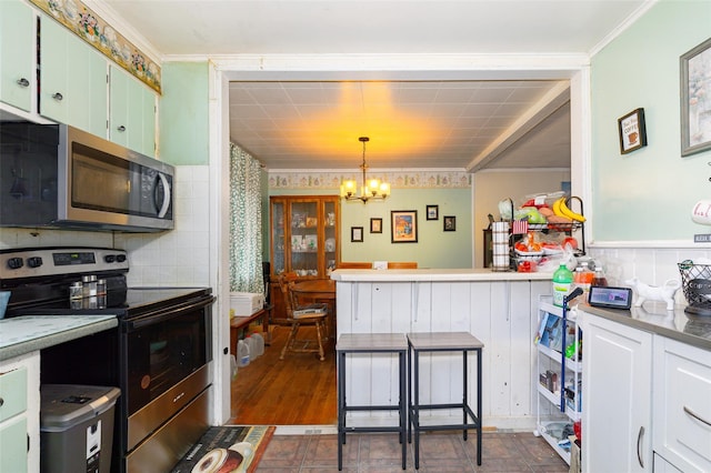 kitchen with decorative light fixtures, a notable chandelier, crown molding, white cabinetry, and appliances with stainless steel finishes