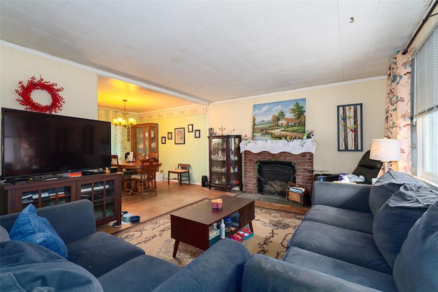 living room with an inviting chandelier, a brick fireplace, crown molding, and hardwood / wood-style flooring