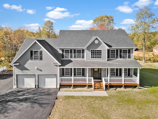 colonial home with a porch, a front yard, roof with shingles, and driveway