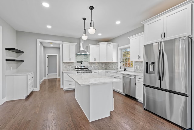 kitchen with stainless steel appliances, dark wood finished floors, a sink, and wall chimney range hood