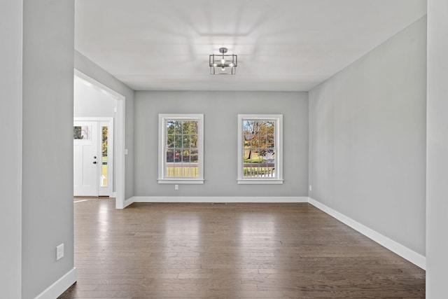 unfurnished dining area featuring dark wood-style flooring and baseboards