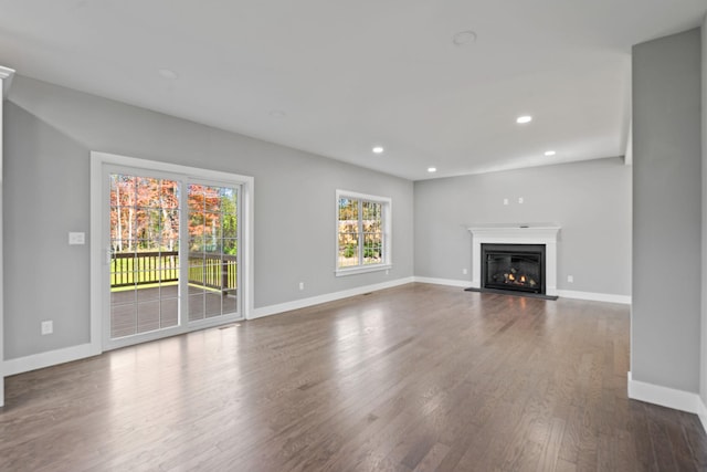 unfurnished living room featuring a glass covered fireplace, recessed lighting, baseboards, and wood finished floors