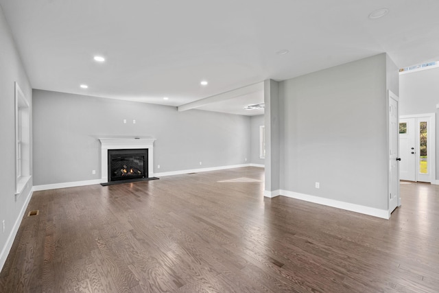 unfurnished living room with recessed lighting, a lit fireplace, baseboards, and wood finished floors