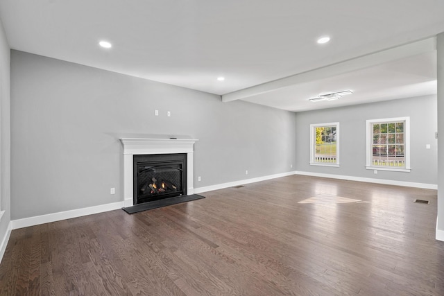 unfurnished living room featuring wood finished floors, a glass covered fireplace, and baseboards