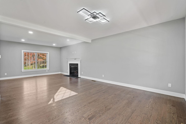 unfurnished living room featuring dark wood-style flooring, beam ceiling, a fireplace, visible vents, and baseboards