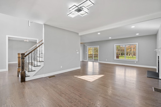 unfurnished living room with baseboards, visible vents, wood finished floors, stairs, and a fireplace