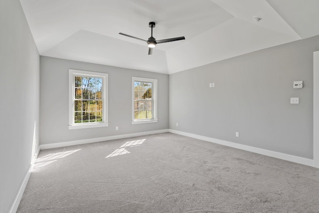 unfurnished room with carpet floors, a tray ceiling, lofted ceiling, a ceiling fan, and baseboards