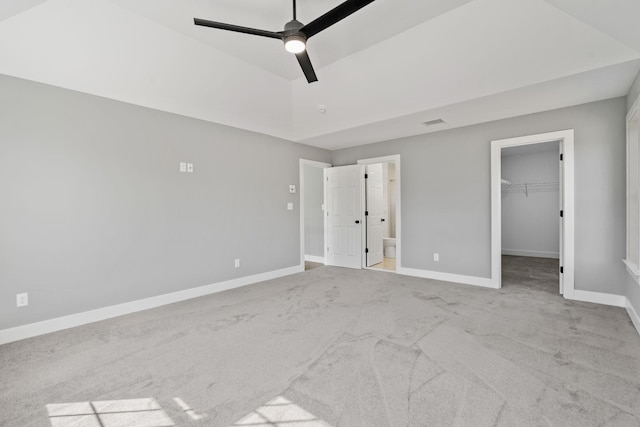 unfurnished bedroom with a walk in closet, visible vents, carpet flooring, connected bathroom, and baseboards