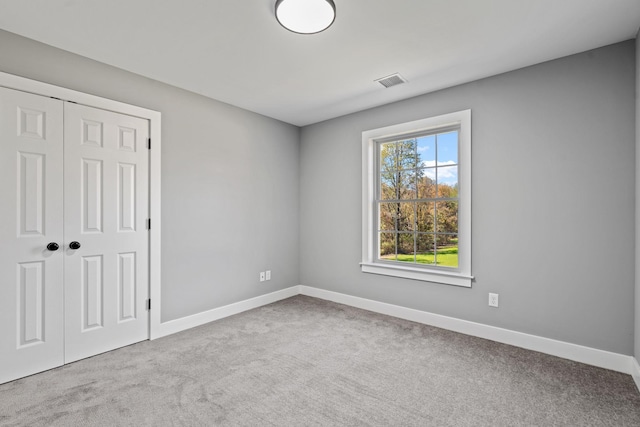 unfurnished bedroom featuring a closet, carpet flooring, visible vents, and baseboards