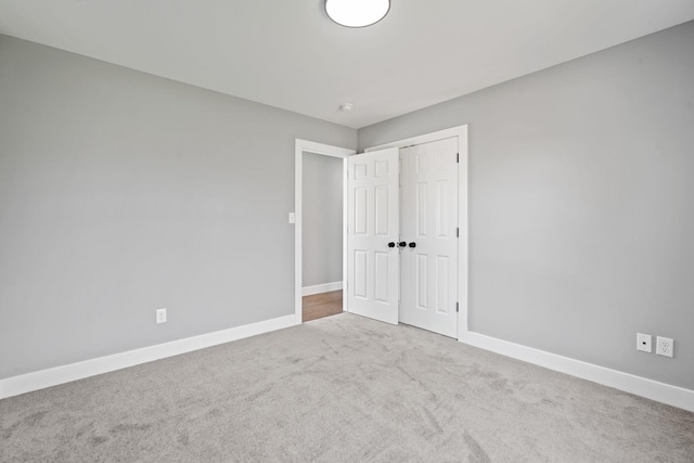 unfurnished bedroom with a closet, baseboards, and carpet flooring