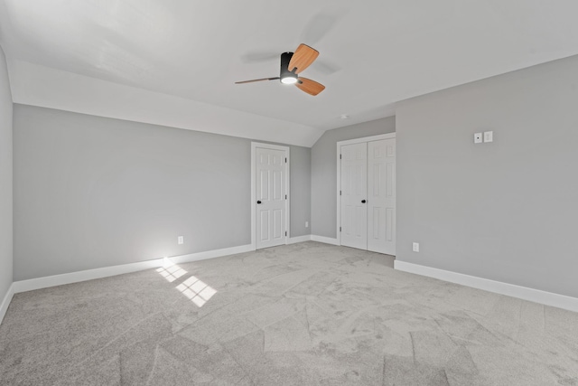 unfurnished bedroom featuring lofted ceiling, a ceiling fan, baseboards, and carpet flooring