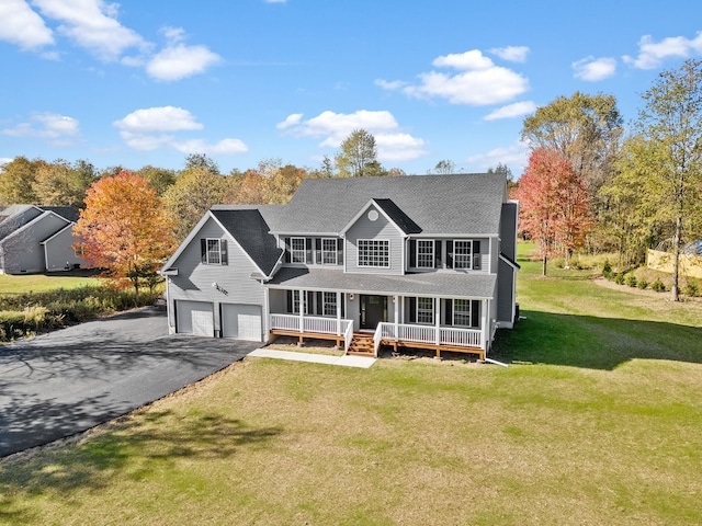 colonial-style house featuring covered porch, driveway, a front lawn, and a garage