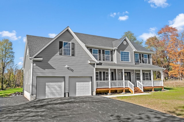 colonial inspired home featuring roof with shingles, covered porch, an attached garage, driveway, and a front lawn