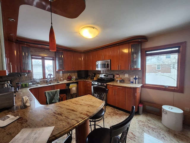 kitchen featuring pendant lighting, kitchen peninsula, decorative backsplash, appliances with stainless steel finishes, and a kitchen breakfast bar