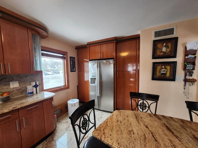 kitchen with light stone countertops, stainless steel fridge, and tasteful backsplash