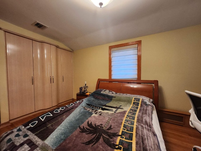 bedroom featuring dark wood-type flooring, a closet, and vaulted ceiling