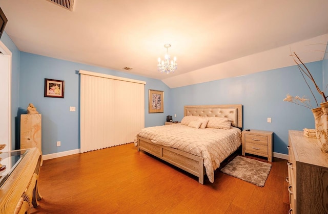 bedroom with lofted ceiling, hardwood / wood-style flooring, and a notable chandelier