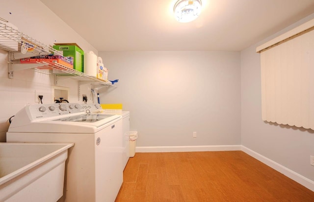 washroom with light hardwood / wood-style floors, independent washer and dryer, and sink