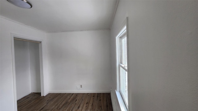 empty room featuring a baseboard heating unit and dark hardwood / wood-style floors