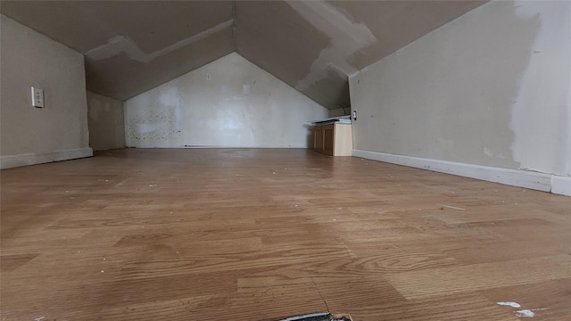 additional living space featuring vaulted ceiling and light hardwood / wood-style flooring