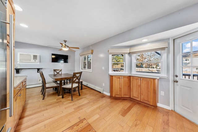 dining area featuring a baseboard heating unit, a wall mounted AC, light wood-type flooring, and a healthy amount of sunlight