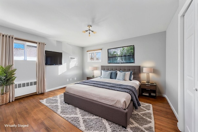 bedroom with baseboards, radiator heating unit, and wood finished floors