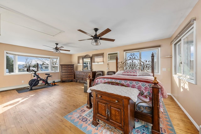 bedroom with attic access, light wood-type flooring, baseboards, and a wall mounted AC