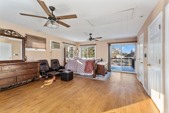 bedroom with attic access, light wood-style flooring, ceiling fan, access to exterior, and a wall mounted AC