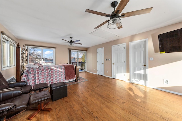 bedroom with access to exterior, attic access, a ceiling fan, wood finished floors, and baseboards