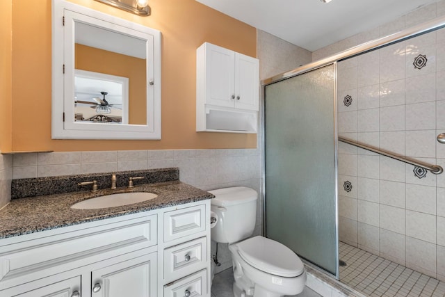 bathroom with toilet, vanity, a shower stall, and tile walls