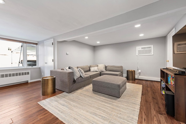 living room with radiator heating unit, a wall unit AC, dark wood finished floors, and baseboards