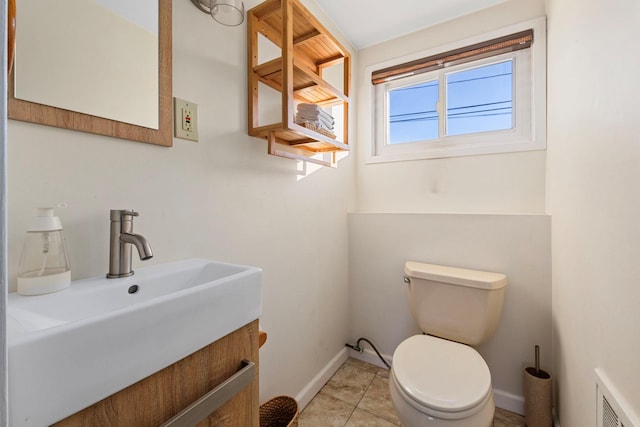 bathroom featuring visible vents, baseboards, toilet, tile patterned floors, and a sink