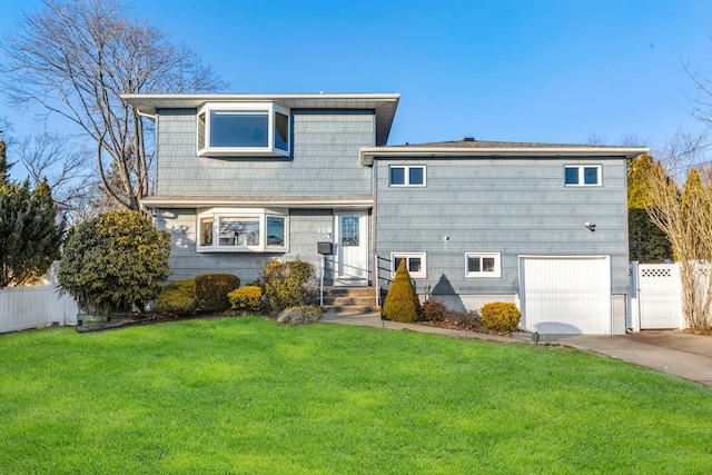 tri-level home featuring a front yard, fence, driveway, and an attached garage