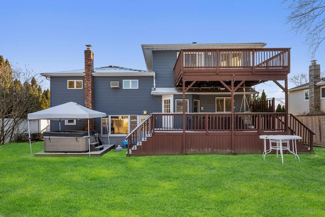 rear view of property featuring a hot tub, a chimney, fence, a deck, and a yard