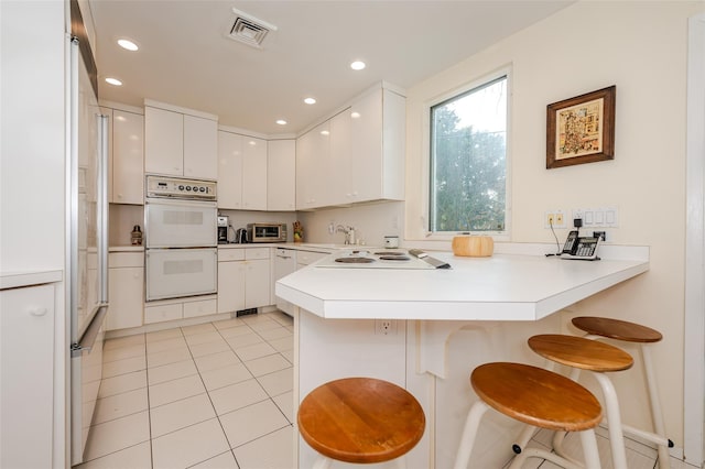 kitchen with a breakfast bar, white appliances, and kitchen peninsula