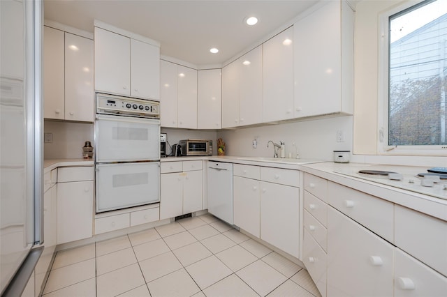 kitchen with light tile patterned floors, sink, white cabinets, and white appliances