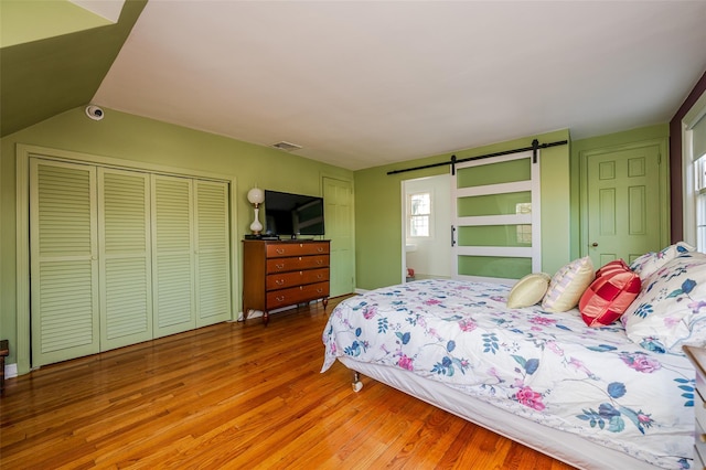 bedroom featuring a barn door, a closet, and hardwood / wood-style flooring