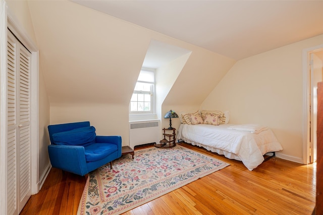 bedroom with radiator, lofted ceiling, and wood-type flooring