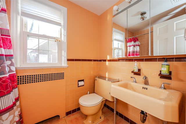 bathroom with tile patterned flooring, radiator heating unit, and a healthy amount of sunlight