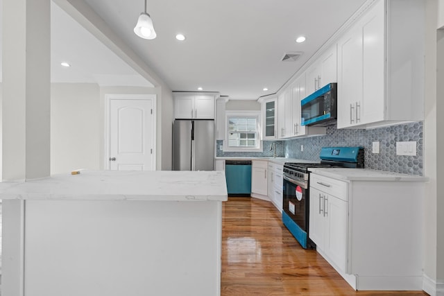 kitchen featuring decorative light fixtures, kitchen peninsula, appliances with stainless steel finishes, and white cabinetry