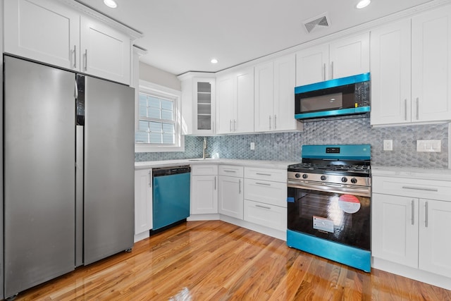 kitchen with light wood-type flooring, stainless steel appliances, and white cabinets